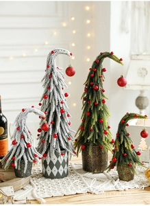Mini Christmas tree with snow, red berries and curved tip on a rustic wooden table