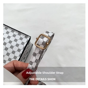 Détail de la bandoulière en cuir blanc ajustable avec boucle dorée sur le sac à main
