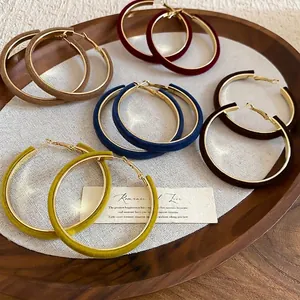Velvet flocked geometric hoop earrings set in assorted colors on wooden tray