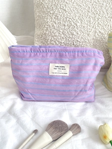 Detail of purple striped canvas cosmetic bag featuring a woven label on soft cotton fabric