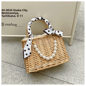 Macro detail of hand-woven straw basket bag with polka dot scarf and pearl handle