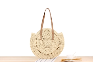 Detail of round paper rope woven beach bag featuring intricate hollow-out spiral patterns