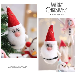 Macro detail of handmade wool felt snowman and Santa Claus ornaments on Christmas tree