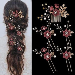 Detail of bridal hair set with burgundy flowers, gold leaves, and pearls on a hair comb