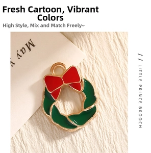 Close-up of a Christmas wreath pendant with green enamel and a red bow in gold metal