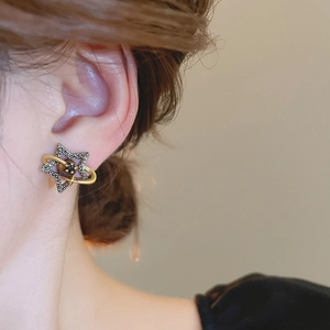 Close-up of vintage gold Saturn star earrings with rhinestones worn by a model
