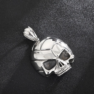 Macro shot of silver skull pendant with dark oxidized details on black leather texture