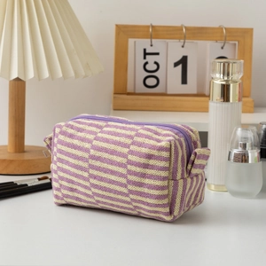Close-up of a purple striped knitted makeup bag with a zipper on a vanity desk
