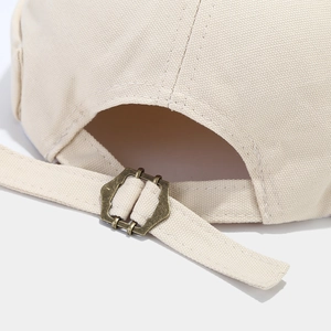 Adjustable beige canvas docker hat with vintage bronze metal buckle and embroidery detail
