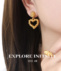 Close-up of golden heart earrings featuring unique wrapped lines and hollow texture on a model