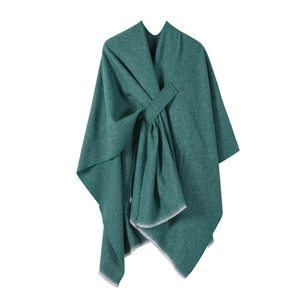 Detail of turquoise knitted poncho wrap showing soft fabric texture and fringe trim