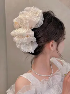 Détail d'une grande pince à cheveux en dentelle beige avec fleurs sur modèle