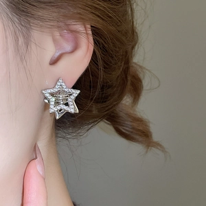 Detailed close-up of a silver star-shaped earring with sparkling cubic zirconia on model