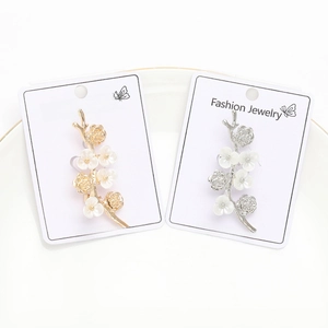 Close-up of gold and silver floral brooches with white petals on a white ceramic plate