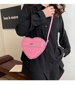 Pink heart-shaped crossbody bag shown on model for size and style reference
