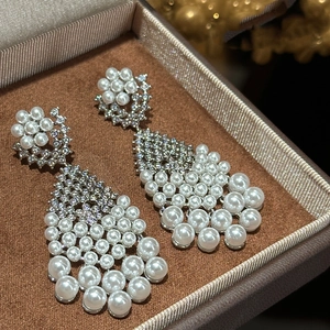 Macro shot of silver tassel earrings with white pearls and crystals in a velvet jewelry box