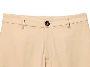 Close-up of beige twill pants featuring a tortoiseshell button and refined waist stitching