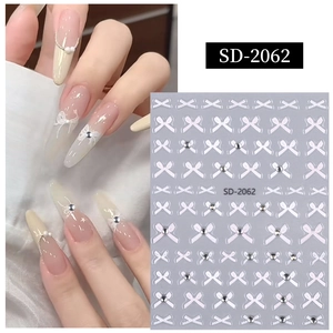 Détail d'autocollants 5D nœuds blancs et strass sur ongles en amande élégants