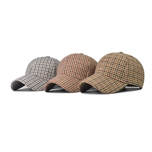 Dettaglio di tre berretti da baseball spessi con motivo pied-de-poule grigio, rosso e giallo
