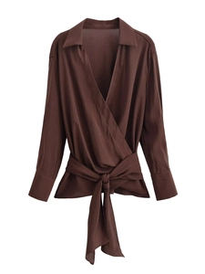 Détail d'un chemisier croisé marron avec ceinture à la taille et manches longues