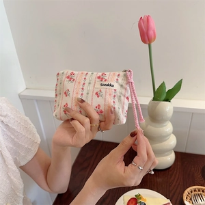 Floral canvas cosmetic pouch with pink drawstring and zipper closure in a cafe setting