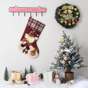 Detail of Christmas stocking with 3D Santa and reindeer designs hanging on a wall hook