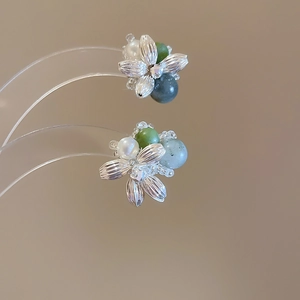 Macro shot of flower earrings with pearls and green agate stones on a luxury display
