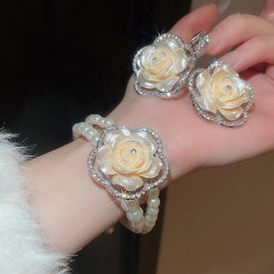 Detailed macro view of multi-layer pearl bracelet and matching diamond flower earrings