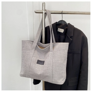 Detail of light gray canvas tote bag with decorative fabric tag and large capacity