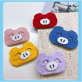 Macro shot of colorful handmade knitted pig charms for DIY hair clips and accessories