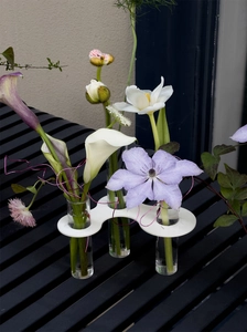 Detail view of a white multi-hole acrylic tube vase with vibrant floral arrangements