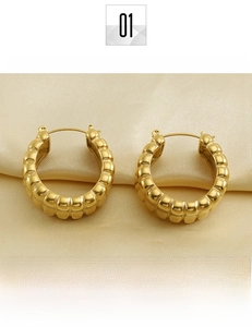 Détail de boucles d'oreilles créoles larges en acier titane doré 18 carats avec poli miroir