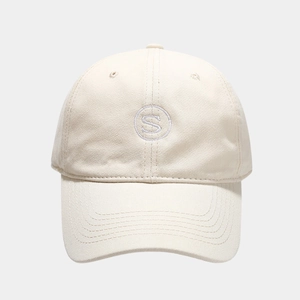 Close-up of S letter embroidery and stitching detail on cream cotton baseball cap