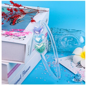 Detail of transparent plastic headband featuring three hearts filled with colorful sequins