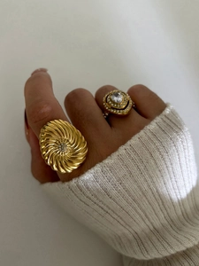 Detail of gold spiral and heart rings with sparkling crystals on a knit sweater cuff