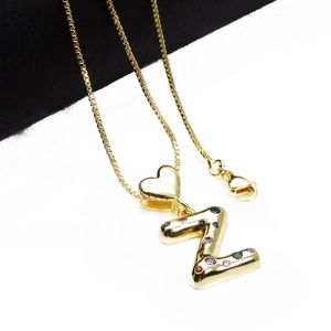 Detail of gold letter Z pendant with colorful zircons and heart-shaped bail on chain