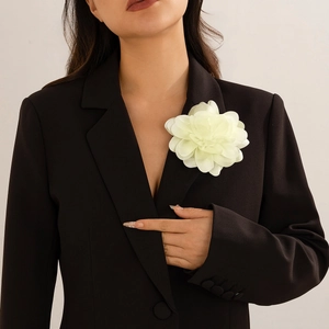 Detail of cream white fabric flower brooch pinned on a black blazer for elegant styling