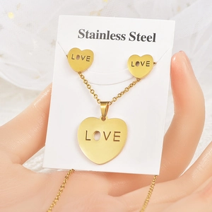 Detailed view of gold stainless steel heart necklace and earrings set with LOVE engraving