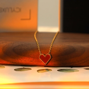 Macro detail of red heart pendant with gold beaded edges on a delicate chain