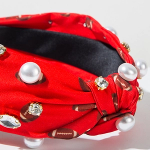 Détail d'un serre-tête football avec perles et strass sur tissu rouge élégant