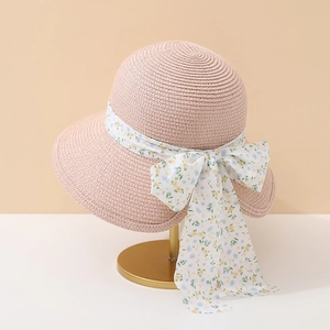 Détail d'un chapeau de paille rose avec ruban à fleurs et nœud élégant pour femmes