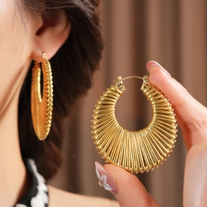 Close-up of golden hoop earrings featuring a unique radial textured pattern and wide band
