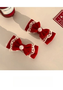 Detail of red velvet bow hair clips with delicate white lace trim and opal-like beads