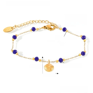 Dettaglio del bracciale in acciaio al titanio dorato con perline blu e ciondolo a conchiglia