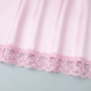 Close-up of pink satin skirt hem featuring delicate floral lace trim and silky texture