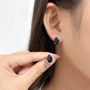 Close-up of black teardrop pear-cut zircon earrings with sterling silver settings on ear