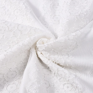 Gros plan sur un tissu en dentelle blanche montrant les motifs floraux et le mesh brodé