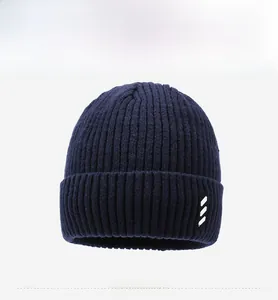 Detailed view of navy blue ribbed knit beanie with folded cuff and small square side patch