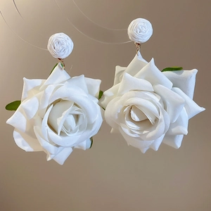 Close-up of white fabric rose earrings with delicate 3D petals for elegant wedding style