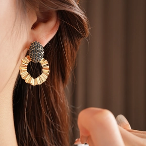 Close-up of gold hoop earring with dark blue gemstone on a model with soft lighting